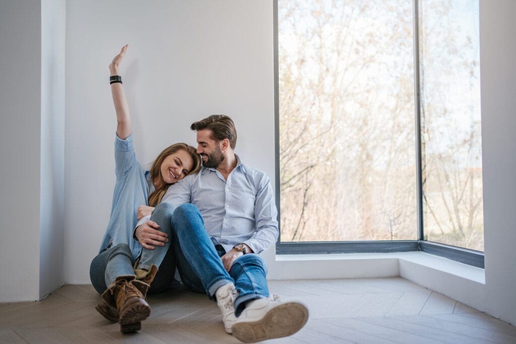 Serene young couple relaxing by the window in their new apartment